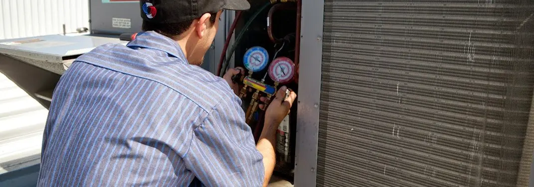 HVAC technician servicing a condenser unit in Keokuk